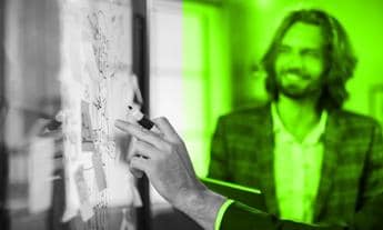 Şeffaf bir tahta üzerinde sunum planı yapan ve notlar alan gülümseyen bir adam figürü; profesyonel sunum becerilerini ve etkili hitabeti simgeleyen yeşil-gri tonlu görsel.